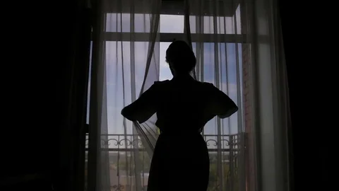 A young woman approaches the window, opens to a balcony, enjoying. morning bride Vidéo 81691939