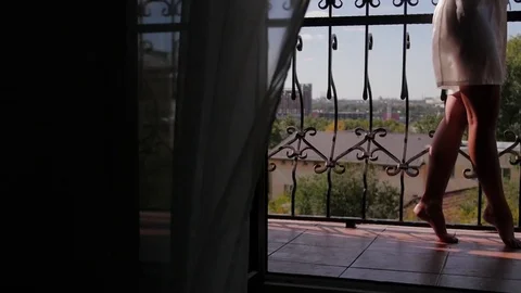 A young woman approaches the window, opens to a balcony, enjoying. morning bride Stock Footage 81692230