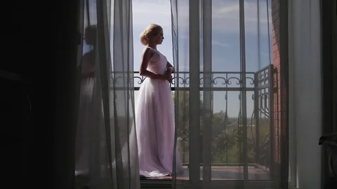 A young woman approaches the window, opens to a balcony, enjoying. morning bride Stock Footage 81715005