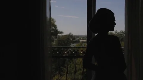 A young woman approaches the window, opens to a balcony, enjoying. morning bride Vidéo 81936595