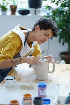 Young woman in apron learning how to make ceramics during masterclass in pottery Stock Photos