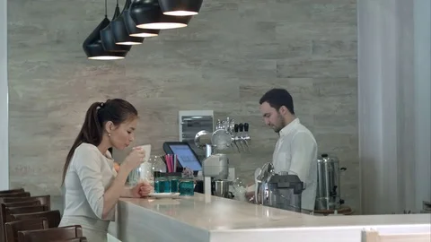 Young woman asking male barista for a bill and paying while sitting at cafe Stock Footage