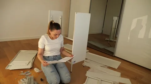 Young woman assembling flat pack furniture at home Vidéo 319406133