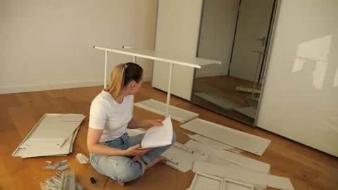 Young woman assembling flat pack furniture at home Stock Footage 319406166