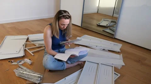Young woman assembling flat pack furniture at home Stock Footage 319406652