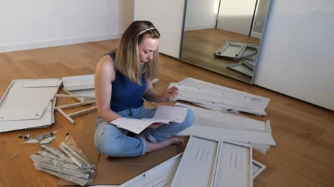 Young woman assembling flat pack furniture at home Stock Footage 319406655