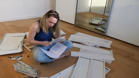Young woman assembling flat pack furniture at home Stock Footage 319406669