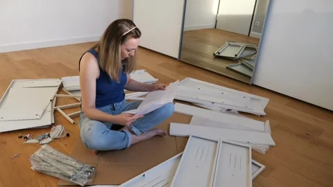 Young woman assembling flat pack furniture at home Stock Footage 319406994