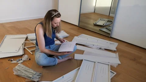 Young woman assembling flat pack furniture at home Stock Footage 319407088