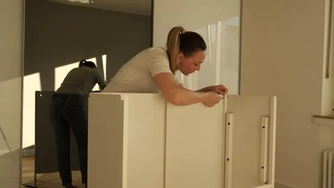 Young woman assembling white flat pack furniture at home Stock Footage 319405537