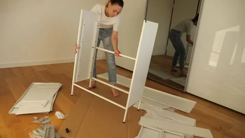 Young woman assembling white flat pack furniture at home Stock Footage 319406060