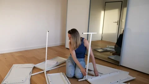 Young woman assembling white flat pack furniture at home Stock Footage 319406631