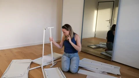 Young woman assembling white flat pack furniture at home Stock Footage 319406656