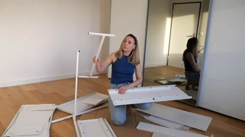 Young woman assembling white flat pack furniture at home Stock Footage 319406661