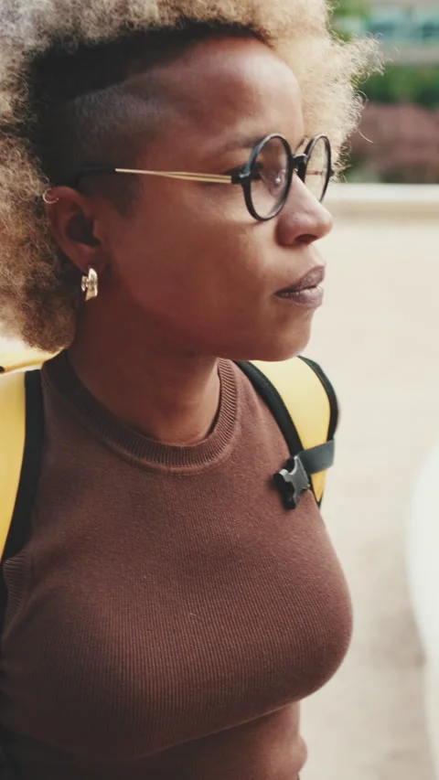 Young woman with backpack walks down the street on modern buildings background Stock Footage 255505586