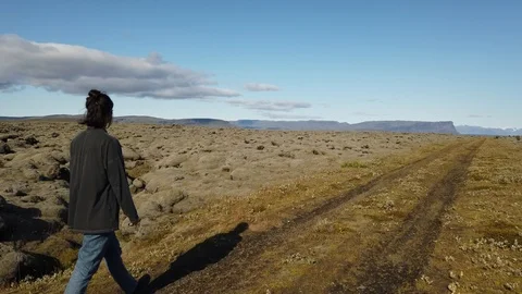 Young woman backpacker walking through spectacular lava fields covered in green  Stock Footage 116030622