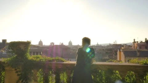Young woman on balcony looks at Rome cityscape Stock Footage