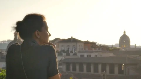 Young woman on balcony looks at Rome cityscape Stock Footage