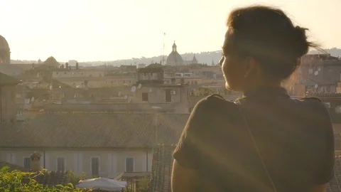 Young woman on balcony looks at Rome cityscape Stock Footage