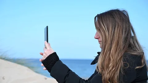 Young woman beach dune using a tablet on a winter windy day Stock Footage 103756445