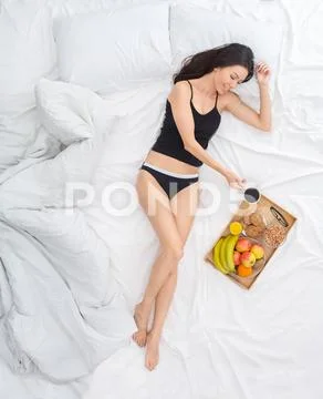 Young woman on bed top view breakfast concept morning refreshment Stock Photos