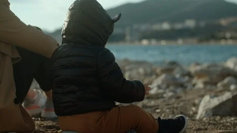 Young woman in a beige trench coat and her 1.5 year old child in a black jacket Stock Footage