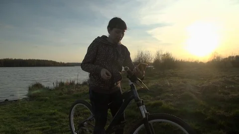 Young woman bicyclist uses phone at sunset. Stock Footage