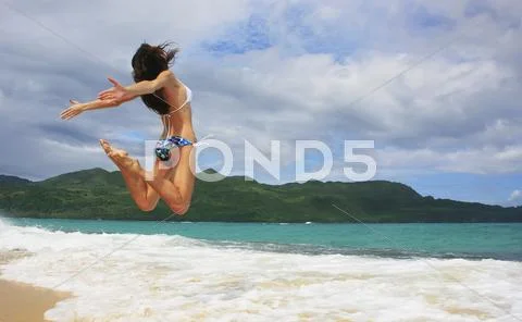Young woman in bikini jumping at rincon beach Stock Photos