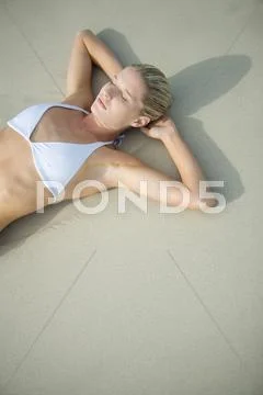 Young woman in bikini lying on beach, waist up ~ Hi Res #42294163