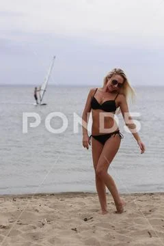A young woman in a bikini walks on the beach in the evening. Beautiful bikini Stock Photos