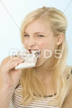 Young woman biting into bar of chocolate, portrait Stock Photos