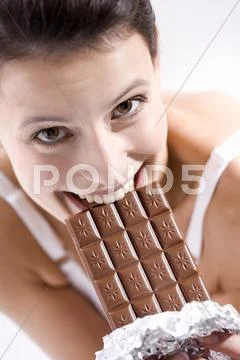Young Woman Biting Into Chocolate Bar, Smiling