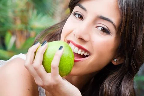 Young woman biting a green apple Stock Photos
