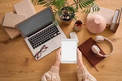 Young woman with blank tablet computer, laptop, headphones and notebook on wo Stock Photos