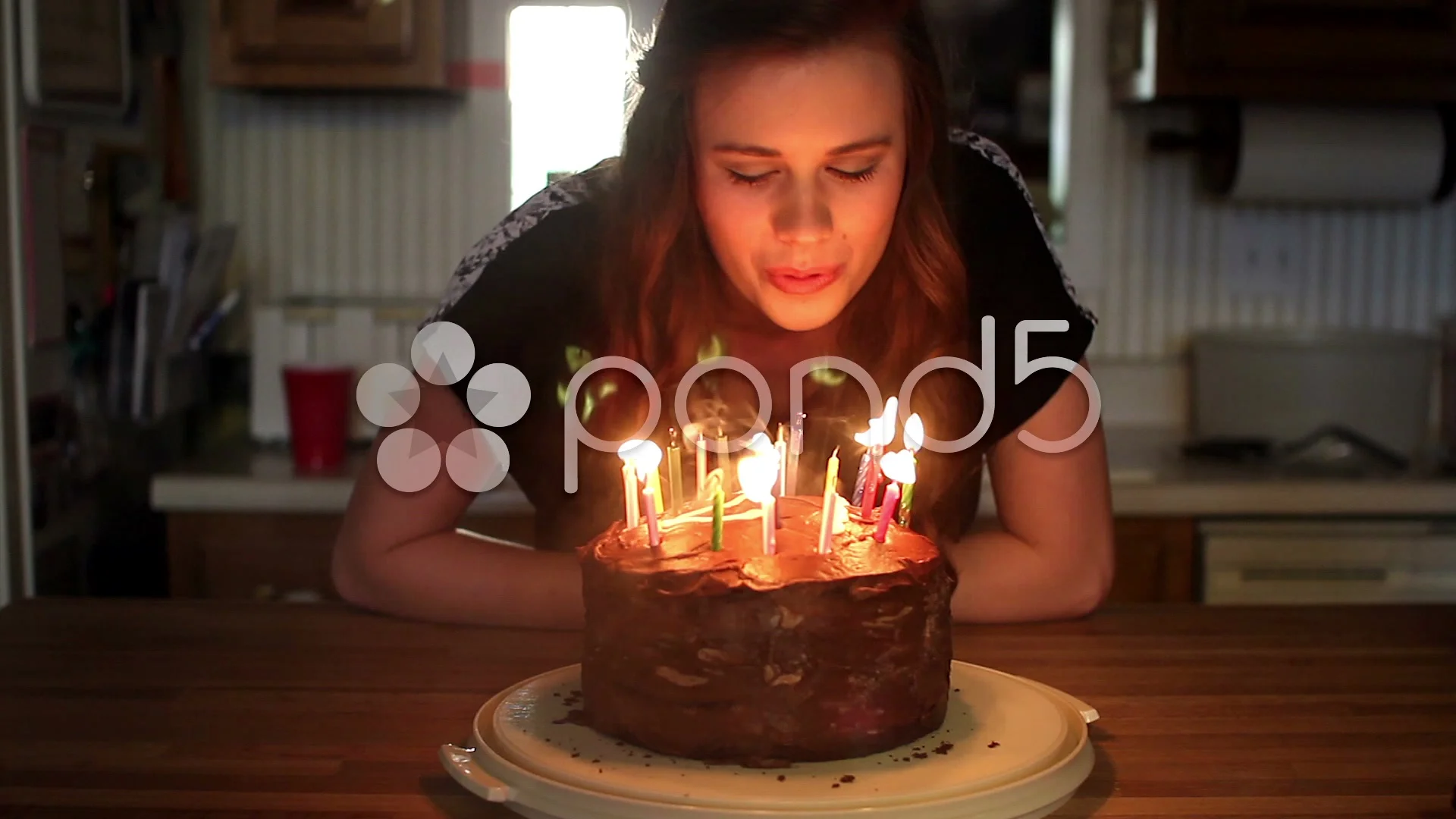 Mixed race woman blowing out candle on birthday cake - Stock Photo -  Dissolve