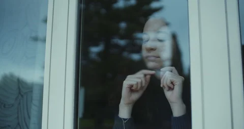 Young woman blowing on window and drawing with her finger Stock Footage 123700634