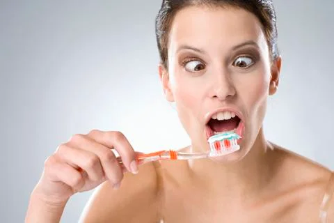 Young woman brushing her teeth, smiling, close up Stock Photos