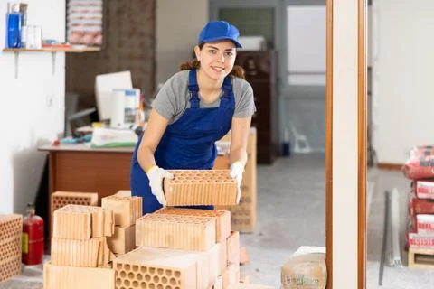 Young woman builder stacking bricks in building site Fotos de archivo