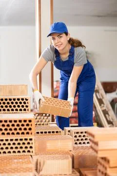 Young woman builder stacking bricks in building site Stock Photos