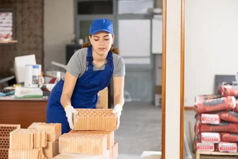 Young woman builder stacking bricks in building site Foto stock