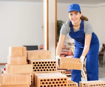 Young woman builder stacking bricks in building site Fotos de archivo
