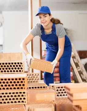 Young woman builder stacking bricks in building site Fotos de archivo