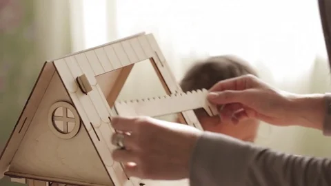 Young woman building dollhouse for her little daughter Stock Footage