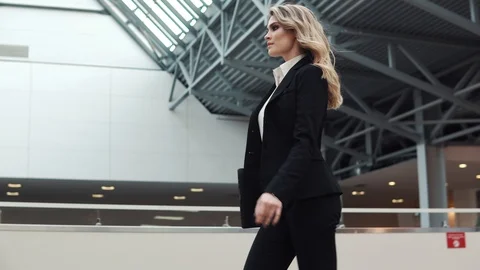 Young woman in a business suit walking on an office building with a laptop in Stock Footage