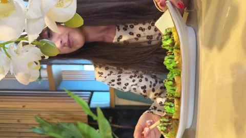 Young woman in a cafe eats backed rolls with sauce with wooden sticks. Vertical Stock Footage 265016056