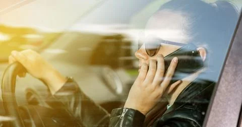 Young woman calling by mobile while driving a car, dangerous phone calling wh 库存照片