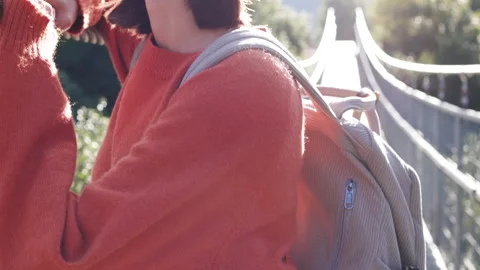 Young woman with a camera and a backpack walks along a suspension bridge. Stock Footage 298149690