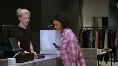 Young woman cannot pay for a purchase by phone at the checkout of a clothing Stockbeeldmateriaal 267488658