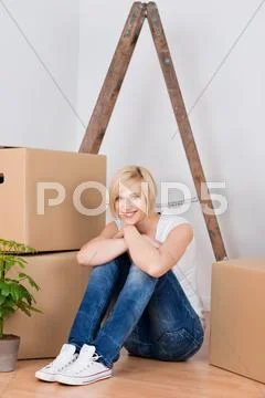 Young woman with cardboard boxes sitting on hardwood floor Stock Photos