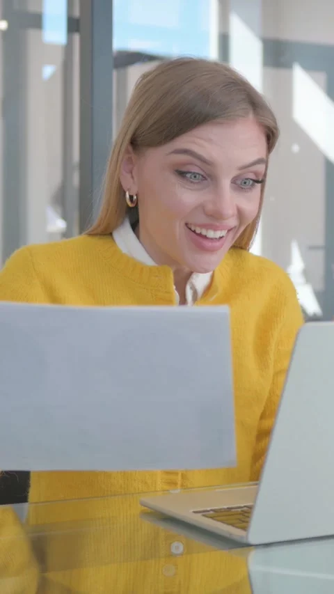 Young Woman Celebrating while Using Laptop and Documents, vertical video Stock Footage 324695201